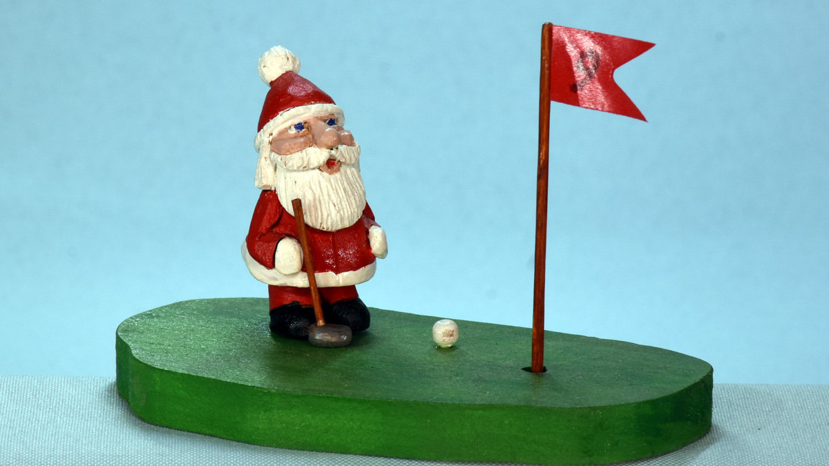 Santa is playing golf, carved and painted by Al Furtado in the 2000s.