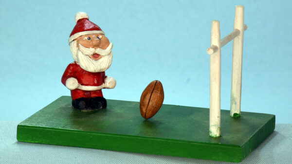 Santa is playing football, carved and painted by Al Furtado.