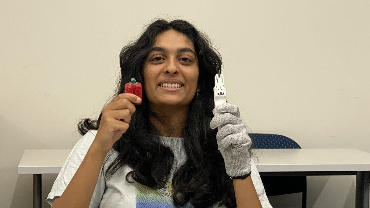 Ambika Palleti smiles while holding a woodcarved red bell pepper and a white rabbit figurine at a Santa Clara Valley Carvers meeting in San Jose, California.