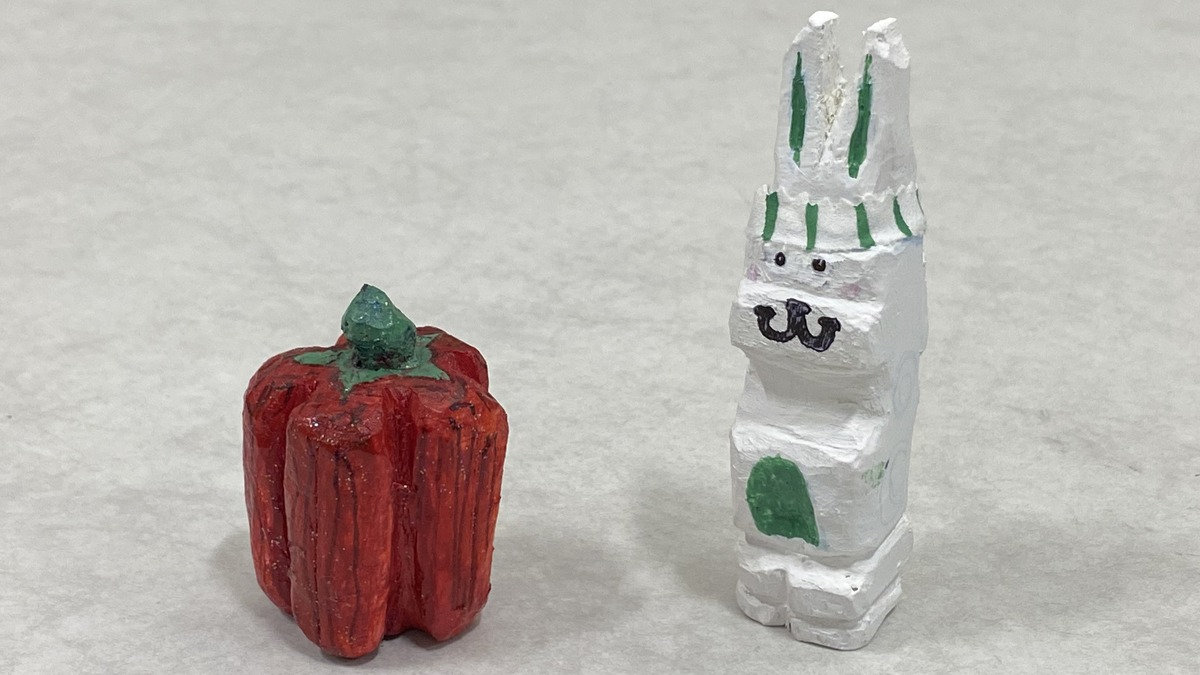 Painted wooden carvings of a red bell pepper and a white rabbit by Ambika Palleti, presented at a Santa Clara Valley Carvers meeting in San Jose, California.