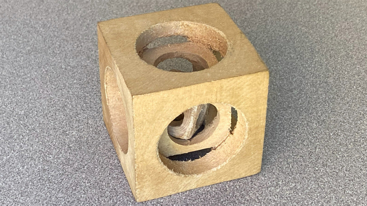Basswood cube titled 'Nested Cubes' with circular openings revealing internal shapes.