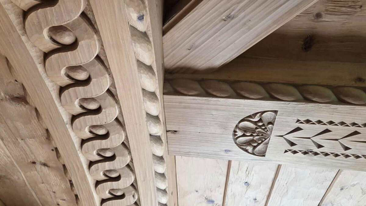 A ceiling with beams decorated with relief and chip carving.