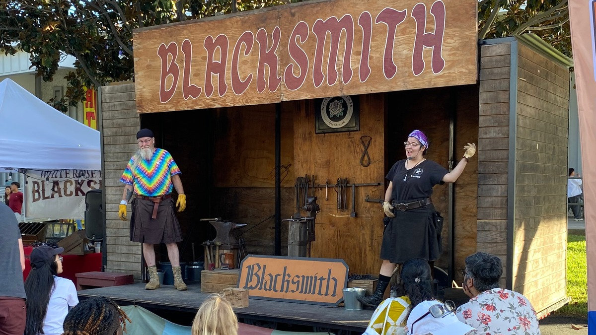 Charles and Somer Johnson of White Rose Forge from Visalia, CA, perform a traditional blacksmithing demonstration at the Santa Clara County Fair in San Jose, California, standing before an anvil and tools.