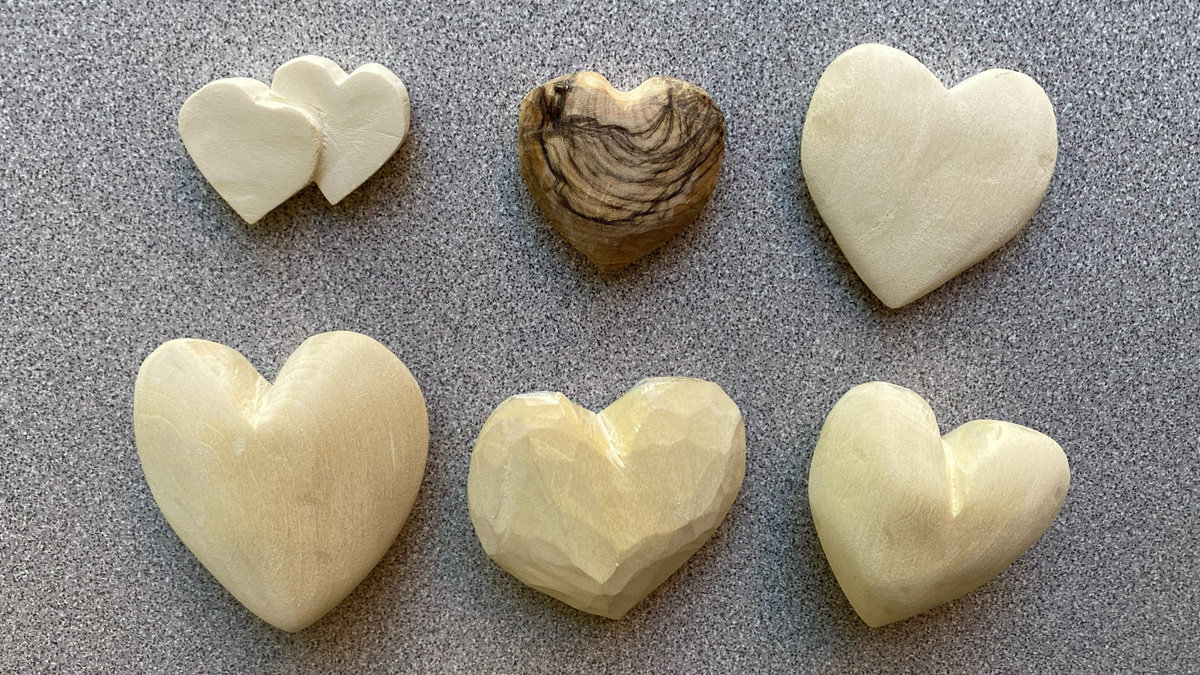 Six hearts that Connie whittled from basswood and olive wood.