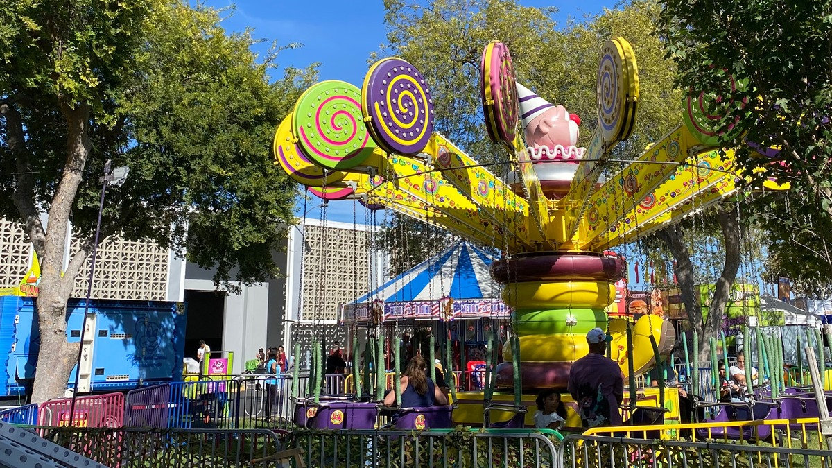 A whimsical carnival ride with oversized lollipops, a giant clown head, and purple seats at the Santa Clara County Fair in San Jose, CA.