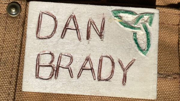 A name badge with a small Celtic knot carved in the top left corner.