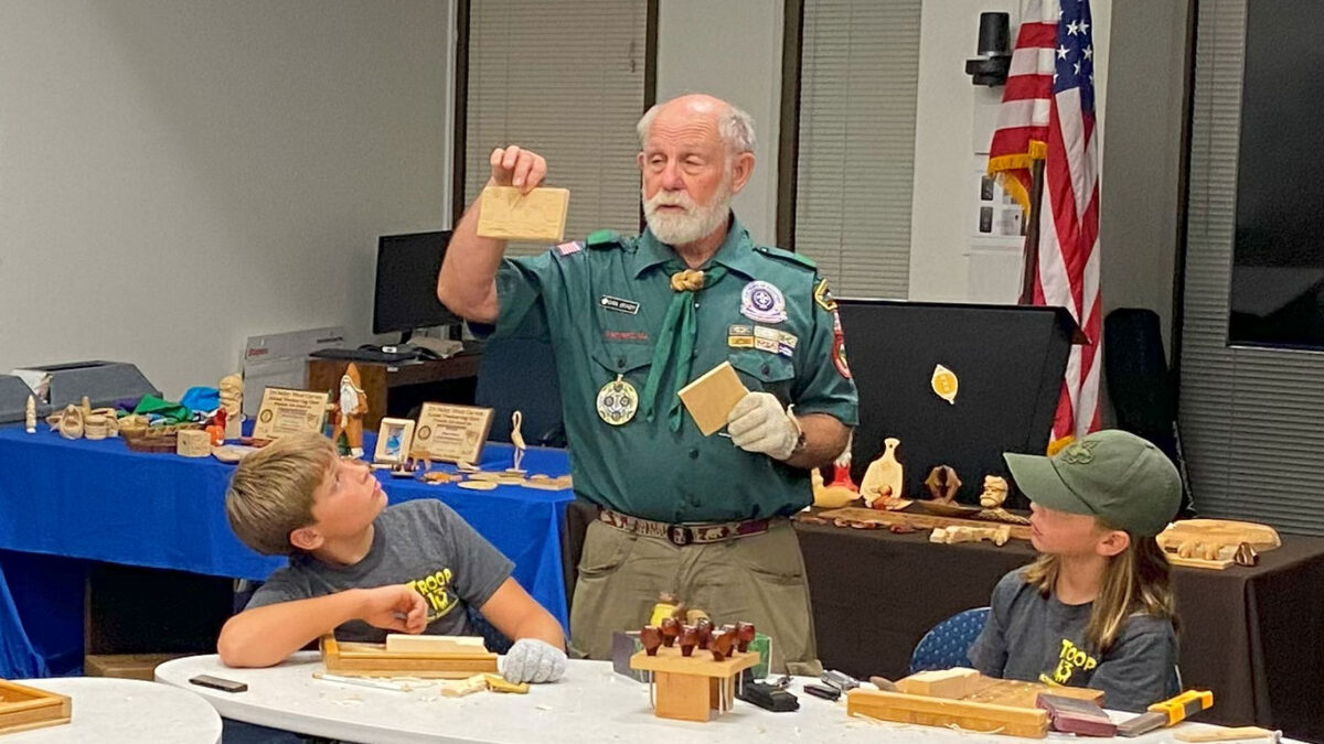 Dan is showing various carving styles to scouts.