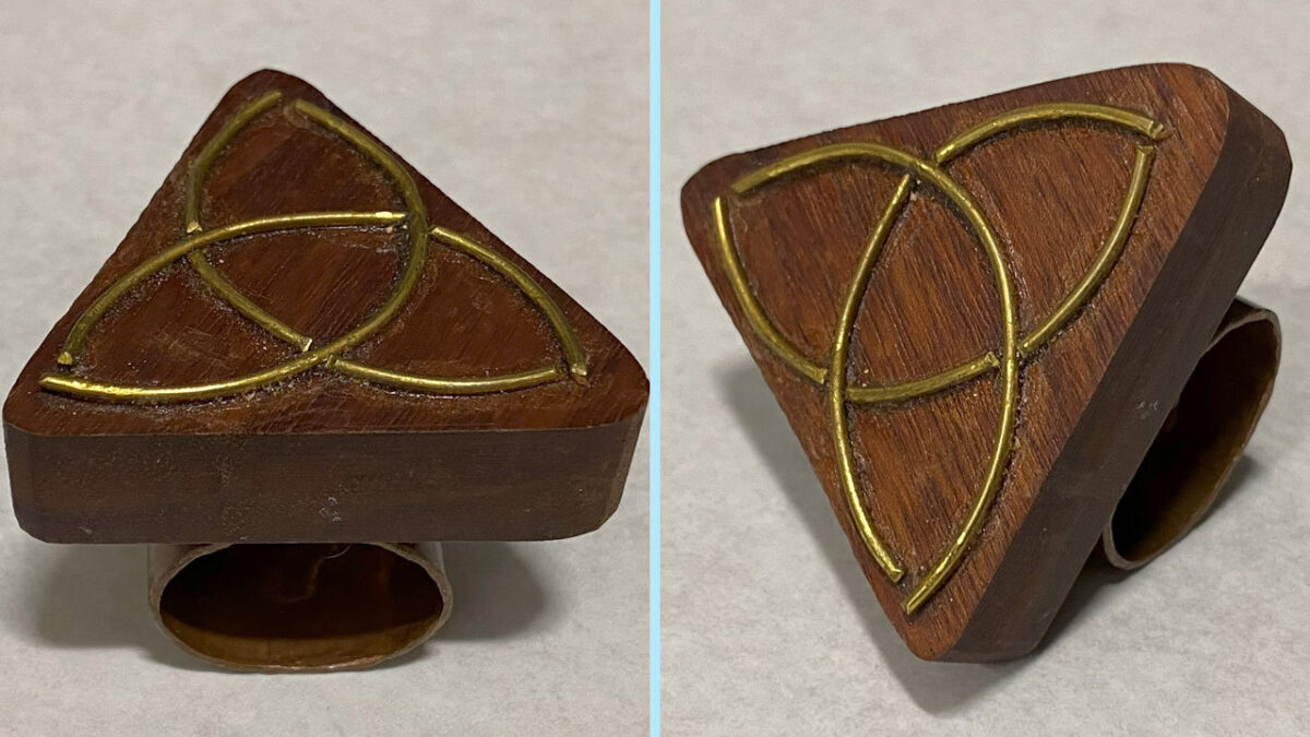 A neckerchief slide carved from walnut and decorated with brass wire forming a Celtic knot.