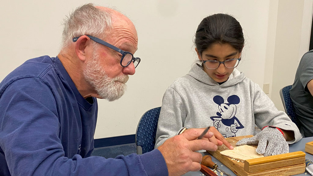 Dan Brady is teaching Zoya Khandpur relief carving. The photo was taken for the SCVC woodcarving newsletter.