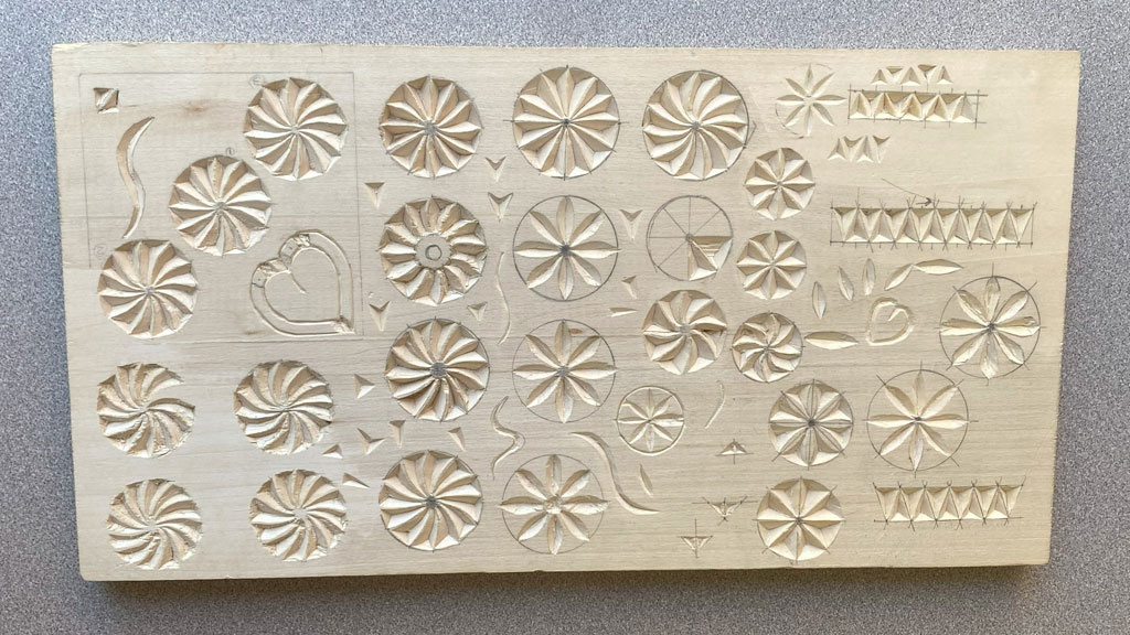 A basswood board with chip-carved rosettes. May 2025.