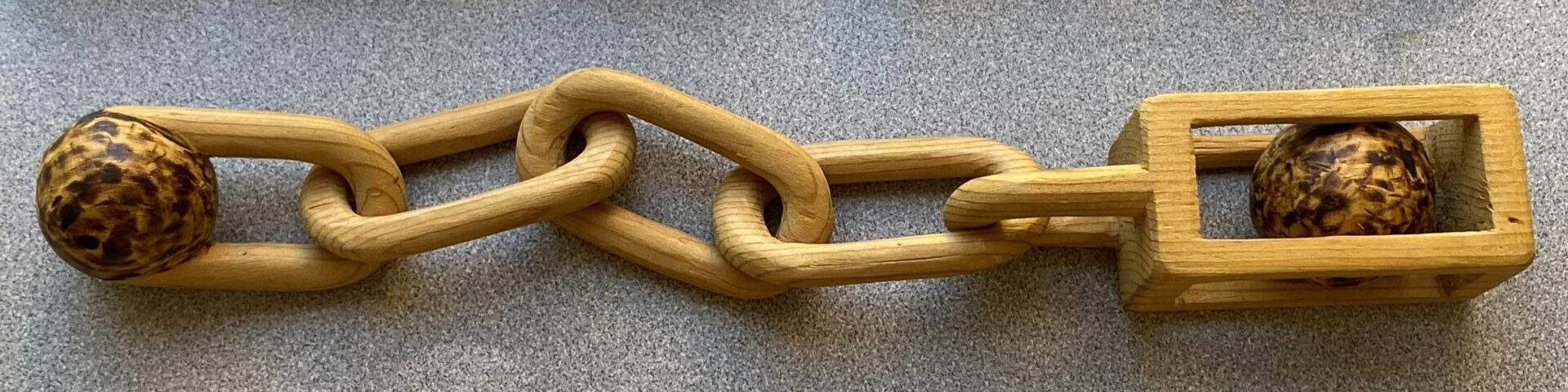 A carved chain with a ball in a cage on one side by David Osterlund, a member of Santa Clara Valley Carvers.
