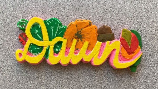 A name badge with flowers carved from basswood and colorfully painted.