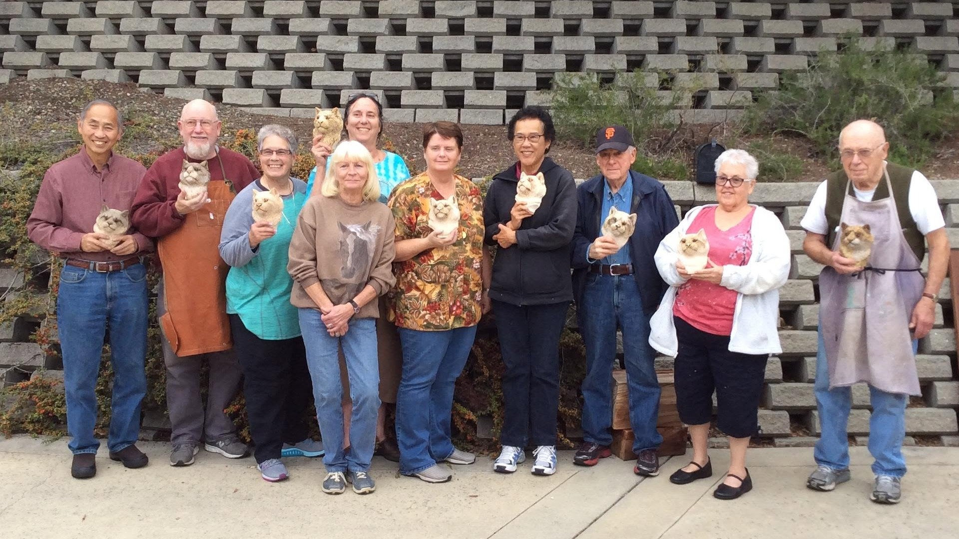 Instructor Debbe Edwards and students from three woodcarving clubs pose with their finished wooden snow leopard busts at a 2016 workshop in Sunnyvale, California.