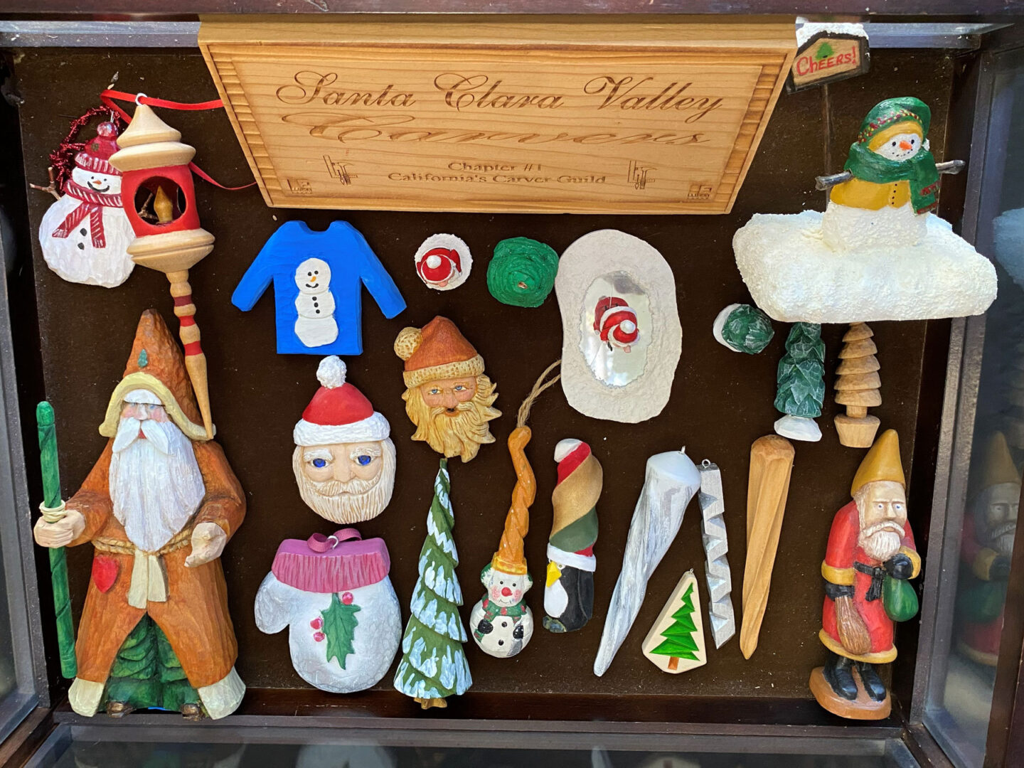 Winter-themed woodcarving projects: Santas, snowmen, various colorful ornaments.