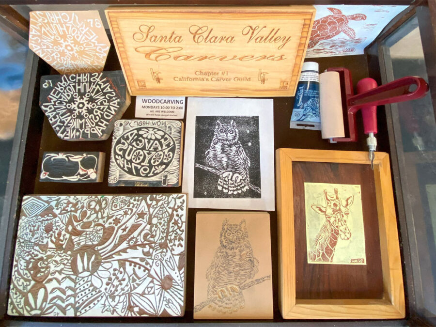 SCVC Woodcarving Display Case showing several carved linoleum blocks and prints on paper, August 2023