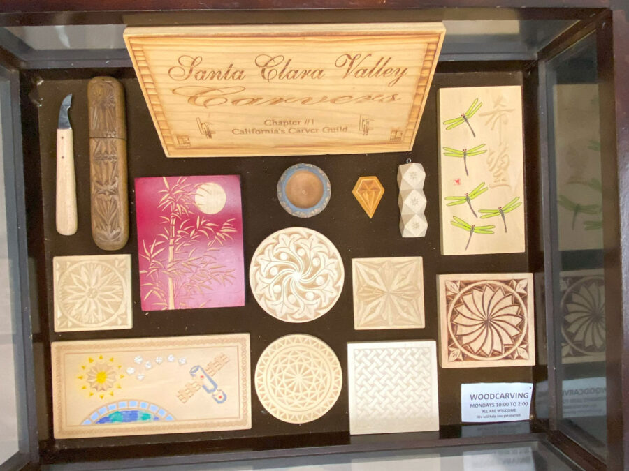 Woodcarving display table features a dozen of chip carving projects and a chip carving knife.