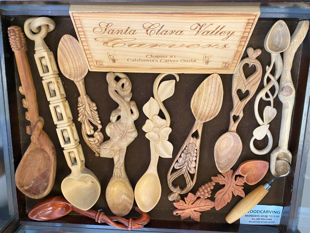 Woodcarving display table features a dozen of intricately carved spoon and a hook carving knife.