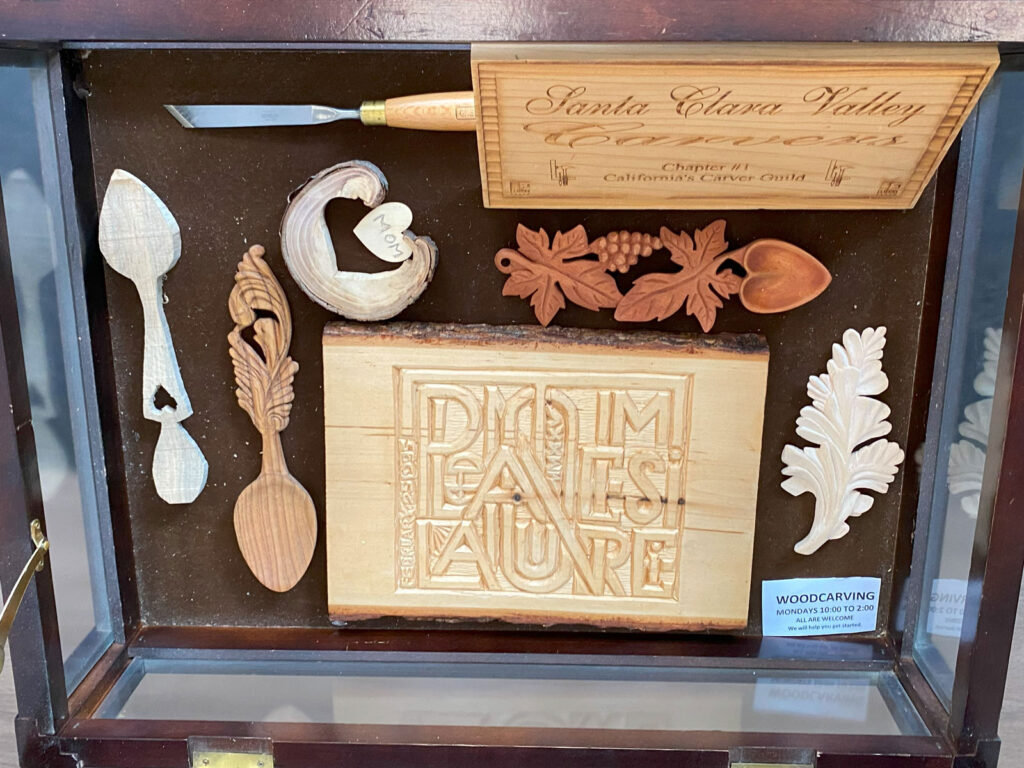 Carved spoons, a chisel, and a plaque.