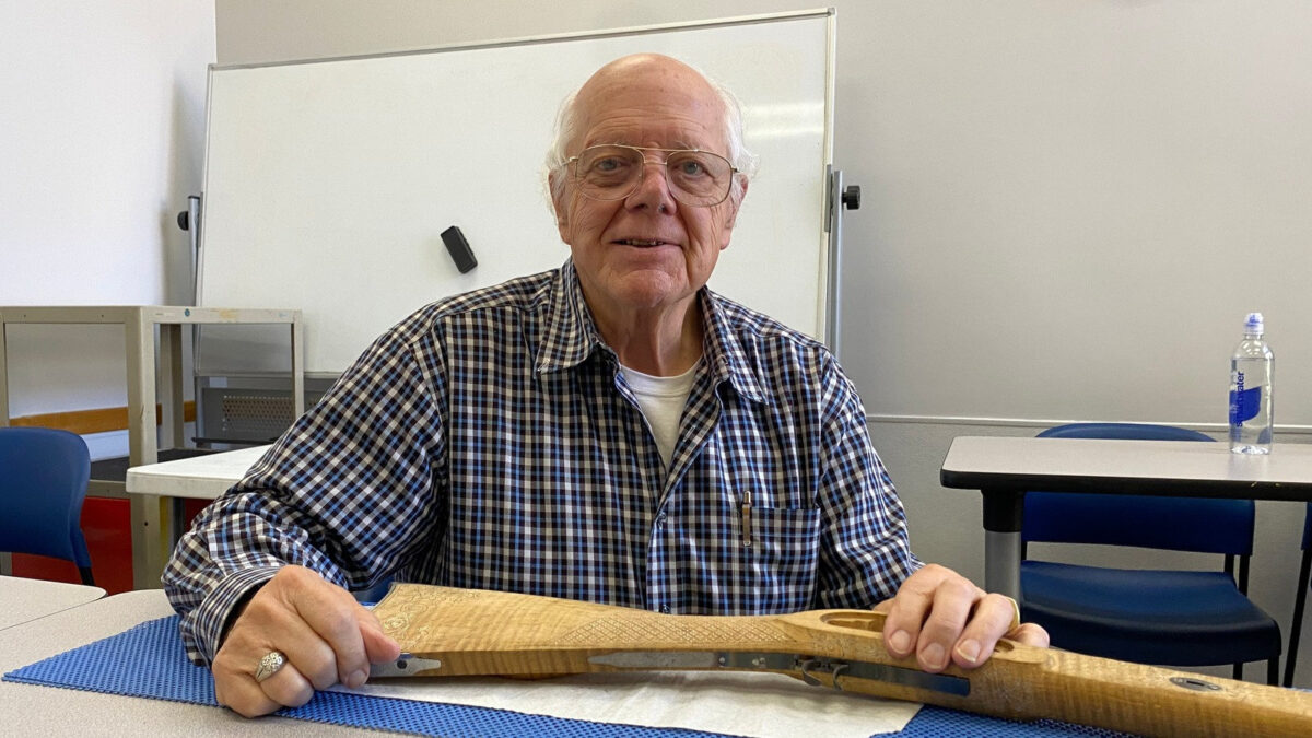 Gary Paulson displays a wooden rifle stock with intricate checkering and silver wire inlay at a Santa Clara Valley Carvers club meeting.