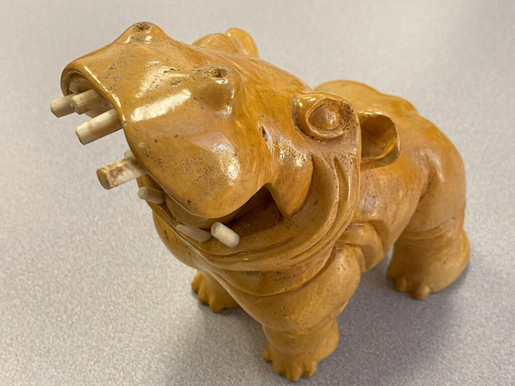 A hippo carved from a Ginkgo tree limb with inserted ivory teeth. About 8" tall.