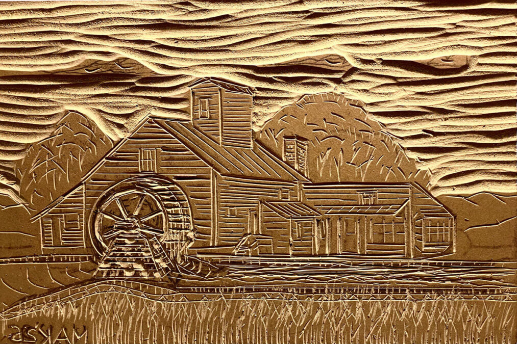 A carved linoleum block depicting the Amherst Grist Mill in relief. The image features a prominent water wheel on the left, the main mill structure, and stylized trees and hills in the background under a wavy sky.