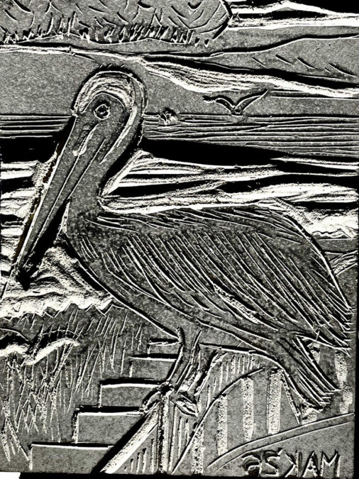 A high-contrast black-and-white image of a carved linoleum block featuring a large pelican standing in profile facing left, set against a backdrop of stylized ocean waves and a distant flying bird.