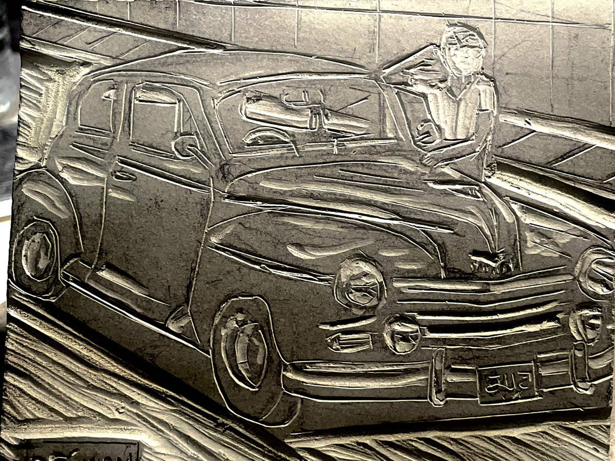 A carved linoleum block depicting a vintage sedan, identified by the filename as a Plymouth Deluxe, angled toward the right. A figure leans casually against the hood of the car, looking upward with one hand near their head. The vehicle features prominent rounded fenders, large headlights, and horizontal grille slats, with a license plate reading "5115" visible on the front bumper.