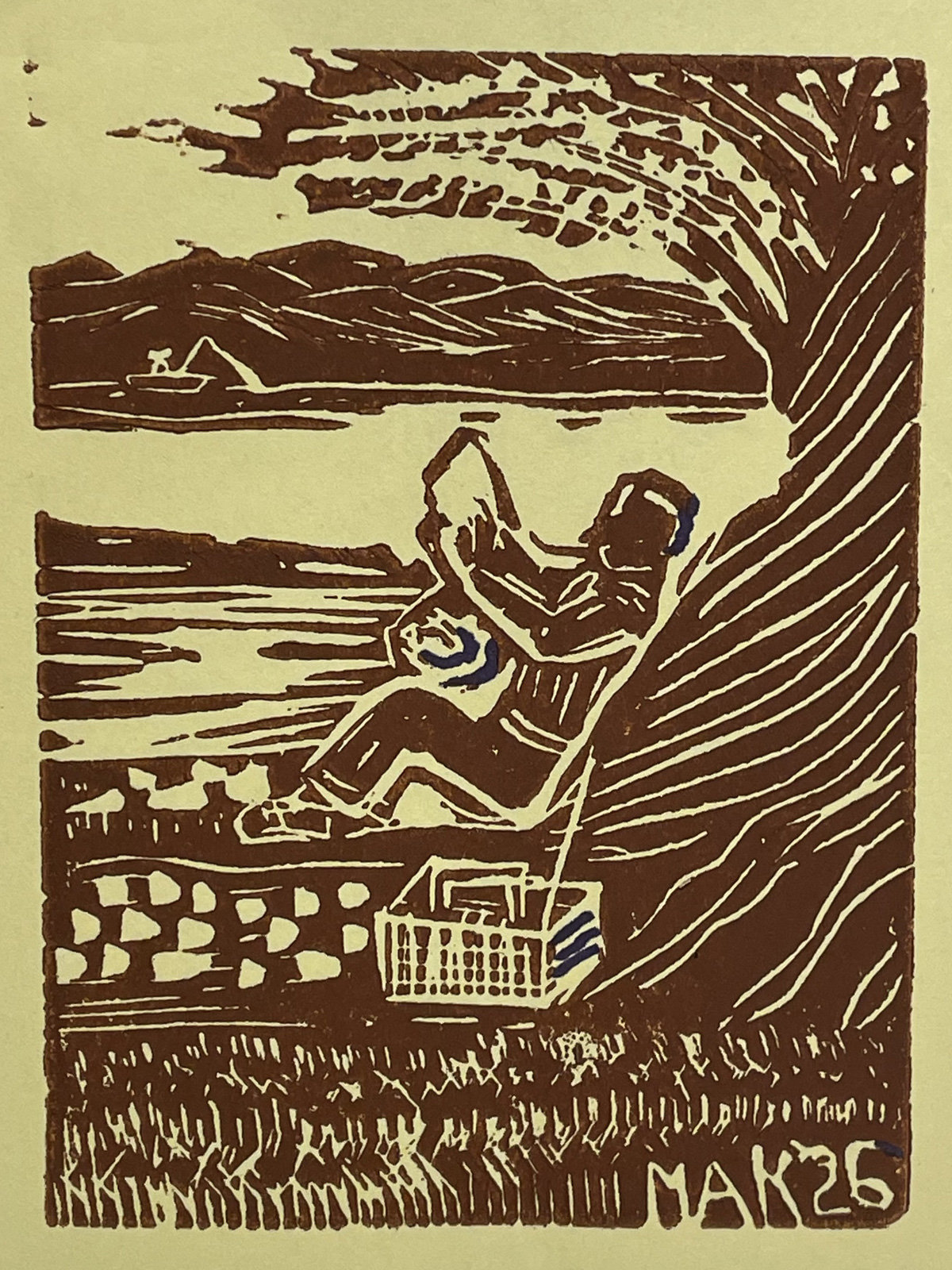 A sepia-toned linoleum block print by Jordan Makower depicting a summer scene based on memory. The image shows a figure relaxing in a folding lawn chair at the edge of a body of water, with a picnic basket resting nearby on the ground. In the background, calm waters stretch toward distant mountains where a small sailboat is visible. Large, stylized tree branches frame the right side of the composition, and tall grass lines the bottom foreground. The print primarily uses brown ink, with small accents of blue on the figure's sleeve and the basket handle. The artist's signature "MAK `26" is visible in the bottom right corner, indicating it was carved and printed in 2026.