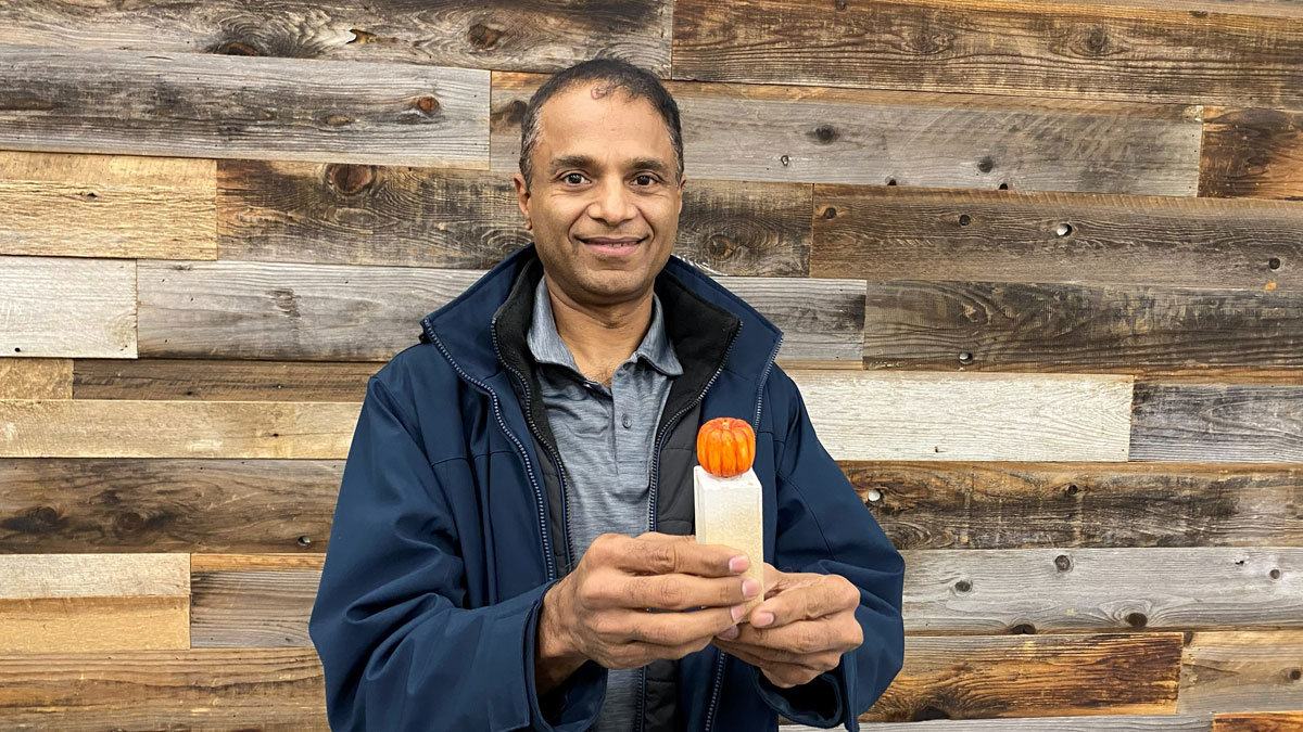 Kim is holding a pumpkin that he carved from basswood. He painted it bright orange.