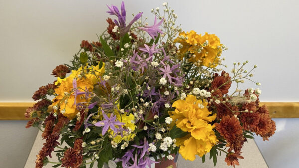 A vibrant floral arrangement of yellow carnations and purple flowers brought by Maureen Johnston for a Santa Clara Valley Carvers meeting at the Los Gatos Adult Recreation Center.