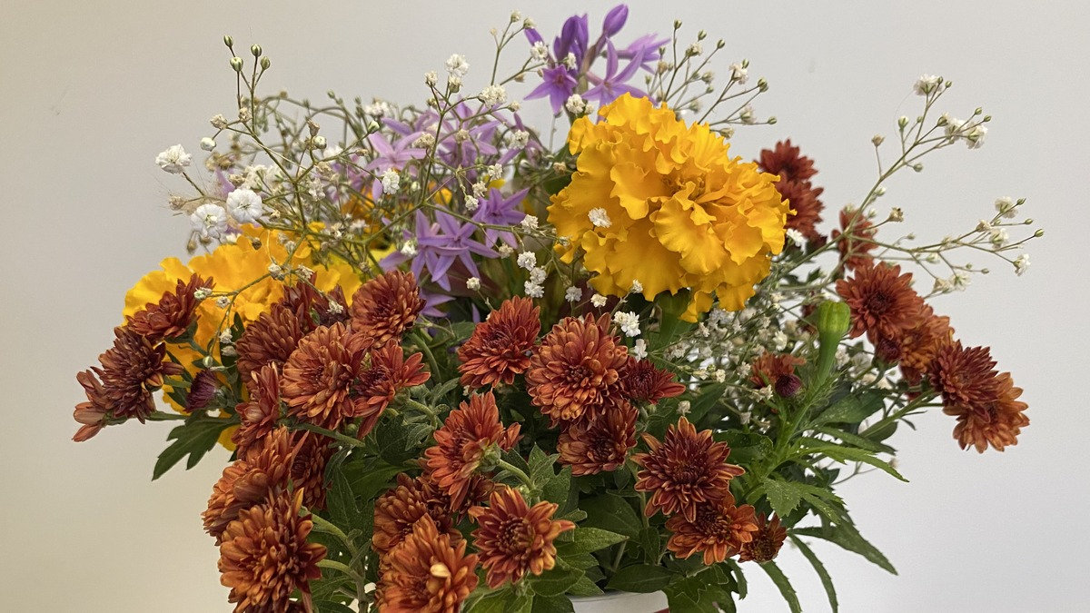 A vibrant bouquet of yellow marigolds, reddish-brown chrysanthemums, and purple flowers grown by Maureen Johnston for a Santa Clara Valley Carvers meeting in Los Gatos, California.