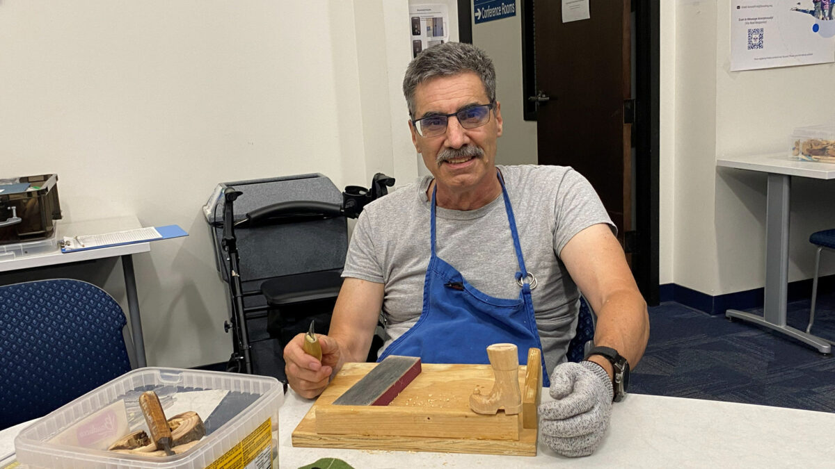 Mike Campi is carving a small basswood shoe.