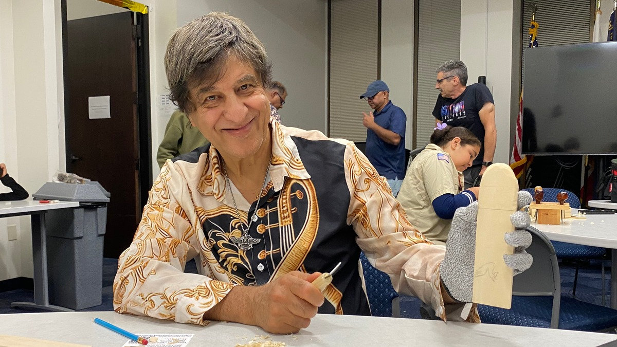 Nejad Mohammad smiles while holding a wood block and carving tool at a Santa Clara Valley Carvers club meeting in San Jose, California.