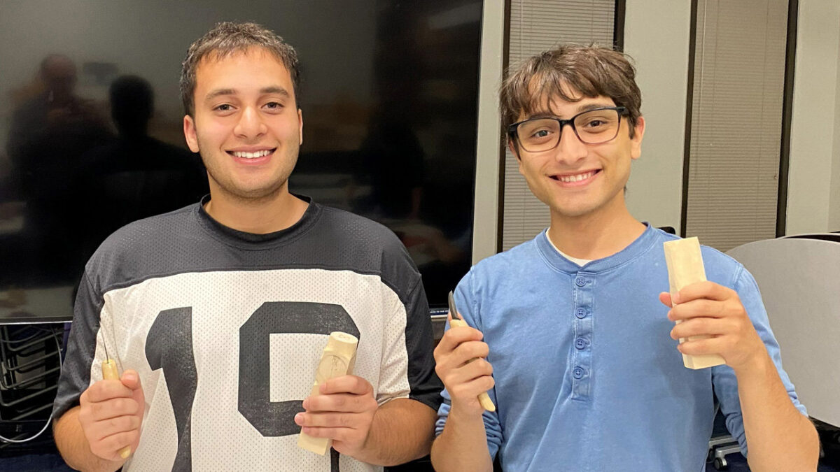 Two smiling club members, Omar Soltan and Tameem Zaidat, hold basswood blocks and carving tools.