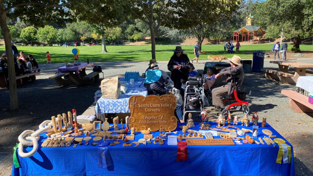 A display table with many woodcarving projects in a local park.