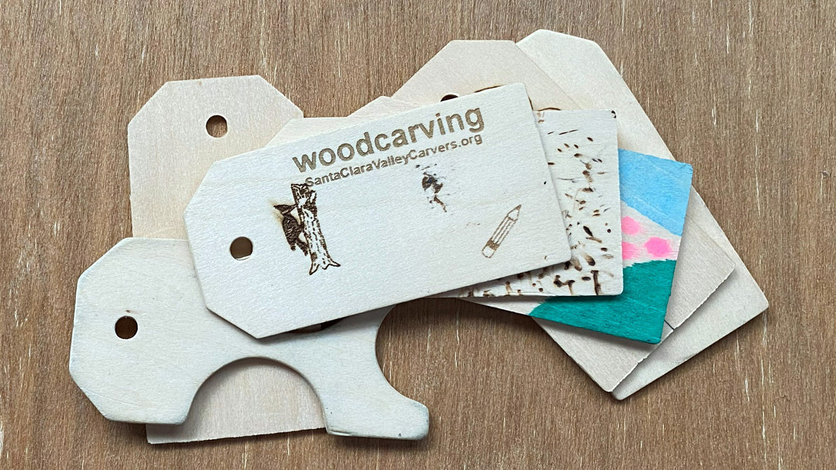 A few small plywood tags. The top one has "woodcarving" and "SantaClaraValleyCarvers.org" woodburned on it.
