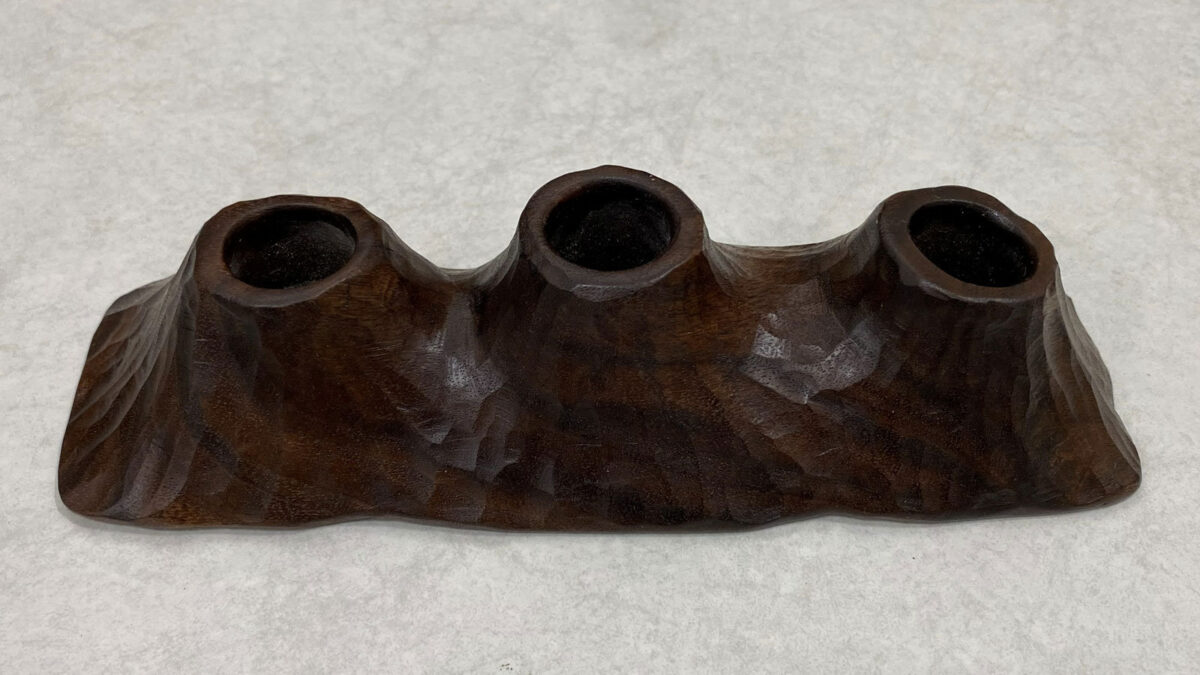A walnut candle holder for three candles; it reminds a mountain range.