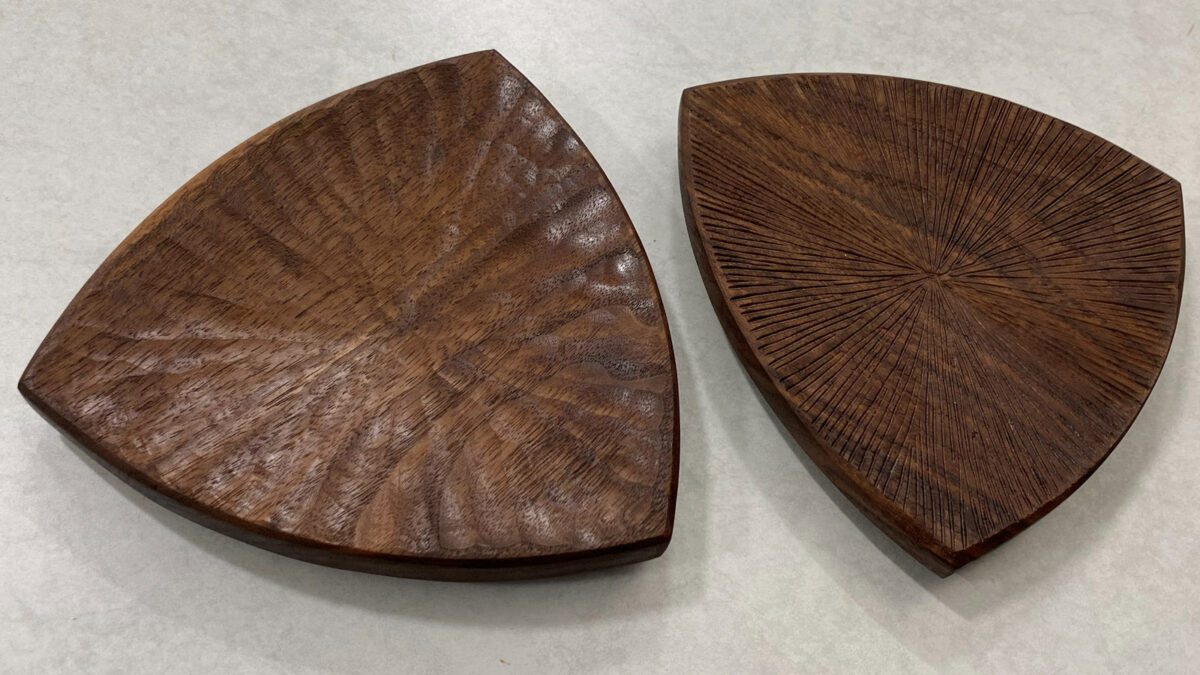 Two triangular coasters with rounded sides, beautifully carved from walnut. The coaster surfaces are textured to achieve a unique rustic look.