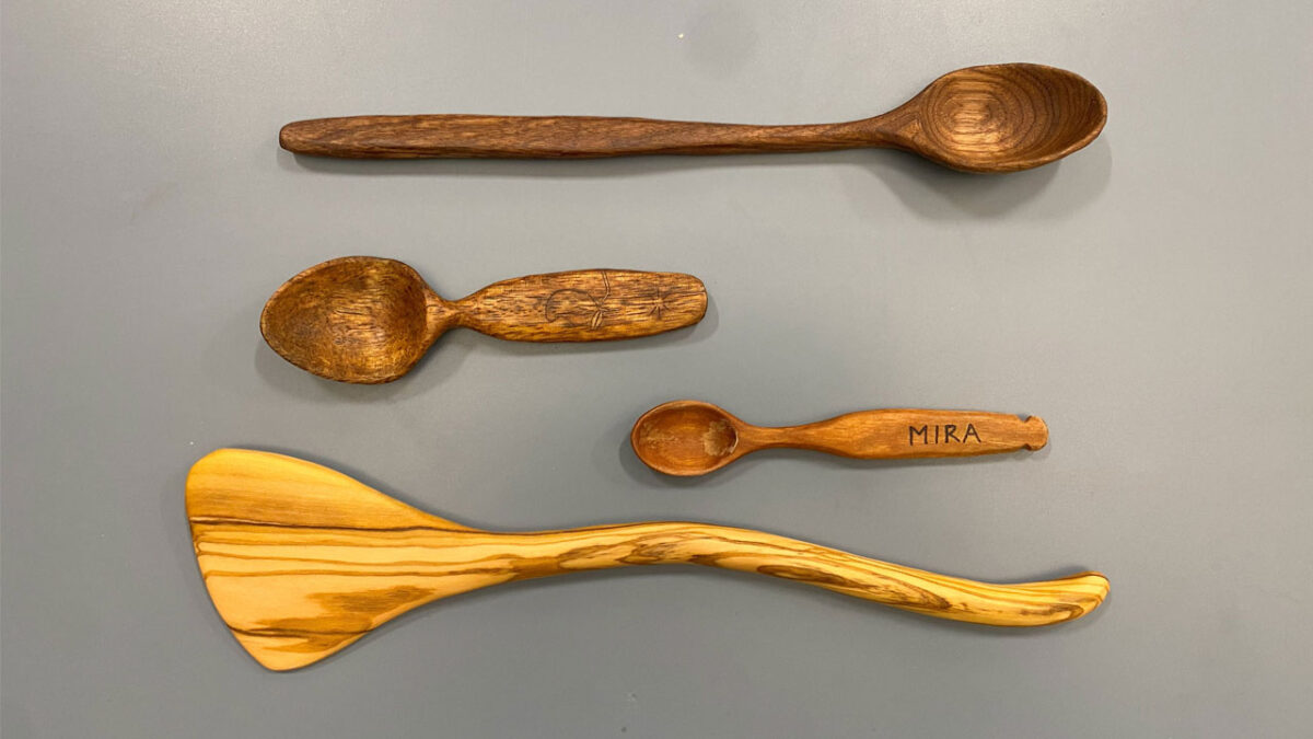 Three wooden spoons and a spatula carved from walnut and apple wood.