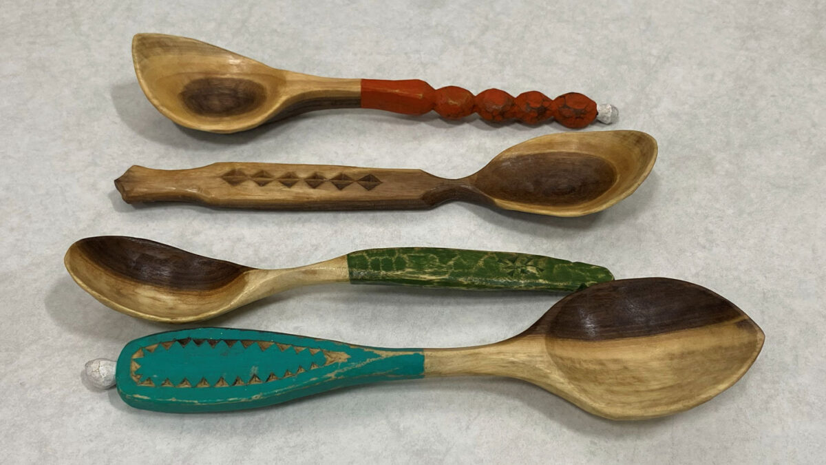 Four simple, utilitarian spoons carved from walnut. The handles are decorated with paint, whittling, and chip-carving designs. The picture was taken for the SCVC woodcarving newsletter.