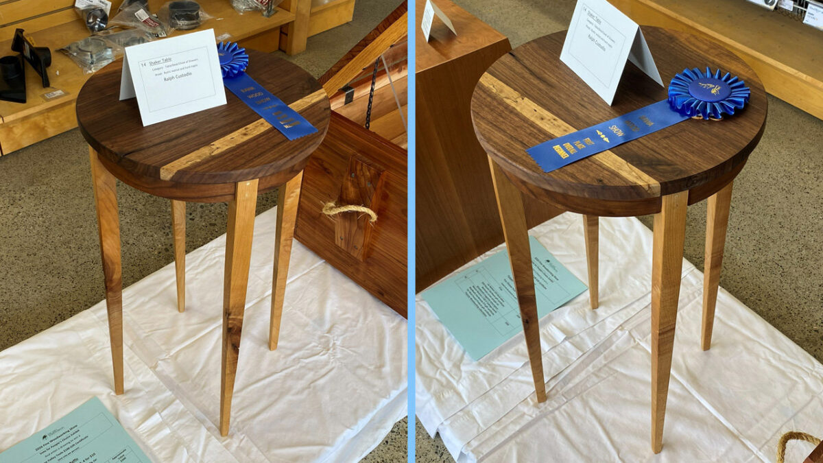 Two side-by-side photographs display a round Shaker-style table made by woodworker Ralph Custodio. The table features a dark wood top with a contrasting light wood inlay strip running across its diameter, supported by four tapered, light-colored legs. A blue ribbon labeled "BAWA Wood Show" lies on the table next to a white card identifying the piece.