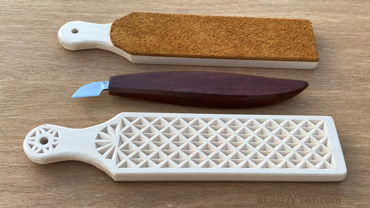 Three woodworking tools are carefully arranged on a light wooden surface. At the top is a leather strop showing its textured brown side and light-colored wooden handle, while in the center sits a chip-carving knife with a dark reddish-brown wooden handle and a sharp metal blade. Beneath the knife lies another leather strop made of basswood, intricately decorated with geometric interlocking triangles across its face and a starburst pattern on its handle. The chip carving patterns for making and decorating DIY leather strops are shared for free download at READ N TRY: https://readntry.com/diy-strop-for-carving-knives/