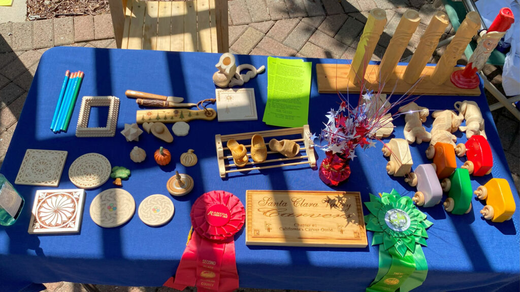 Wood carving and whittling projects on the table at Saratoga Blossom Festival.