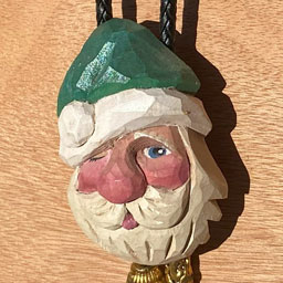 A miniature Santa head ornament carved from basswood and painted.