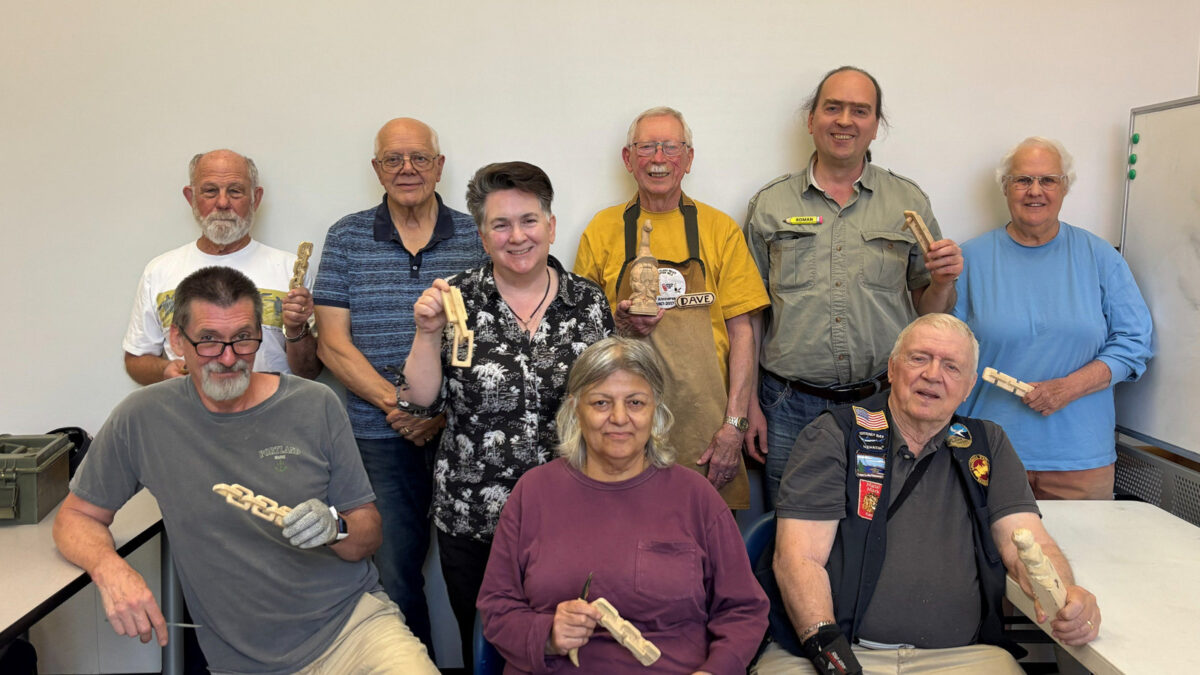 A group photo of members of the Santa Clara Valley Carvers club. The photo was taken during our carving-chain workshop in 2026, so most carvers are holding partially carved wooden chains.