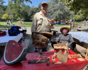 Roman and David show wood carving projects to park visitors at Oak Meadow Park in Los Gatos