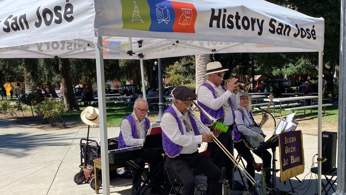 The Silicon Gulch Jazz Band, wearing purple vests, performs under a white tent at the Cars in the Park event at History Park in San Jose, California.