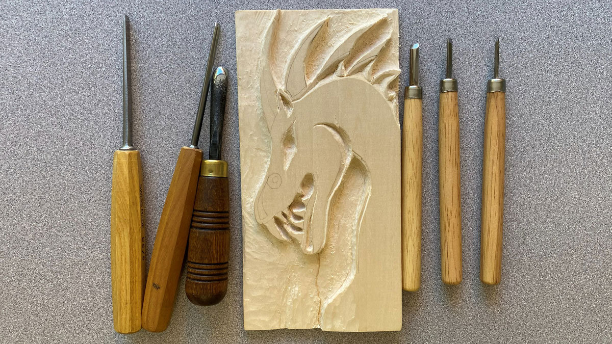 A basswood board with the dragon design. The photo also includes woodcarving tools.