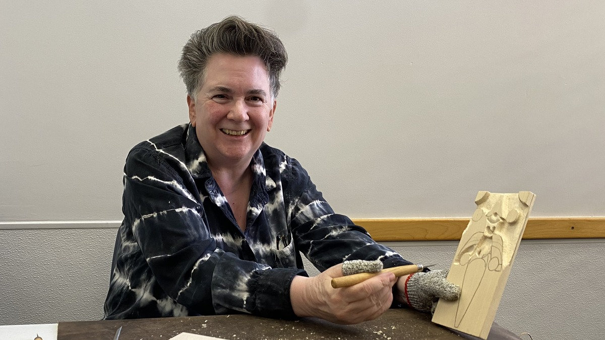 Terry Davis smiles while holding a relief woodcarving and a skew carving knife at a Santa Clara Valley Carvers meeting in Los Gatos, California.