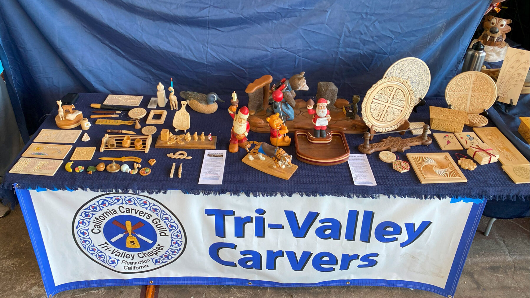 Woodcarving projects on a display table at Maker Faire Bay Area, 2024